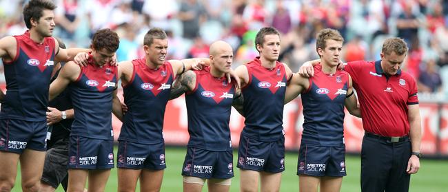 Melbourne players Stefan Martin, Josh Tynan, Brent Moloney, Nathan Jones, Jack Grimes, Jack Trengove and coach Mark Neeld during the national anthem. It was Tynan’s debut for the Demons in Round 1, 2012.