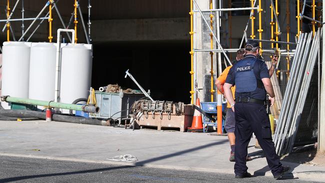 Police search behind a construction site near where the woman’s body was found by members of the public in Toowong. Pic: Jack Tran