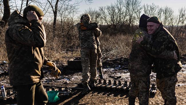 Soldiers from the Ukrainian armed forces' 10th brigade embrace colleagues as they repair a T-72 tank track in the Donetsk region, eastern Ukraine. Picture: AFP