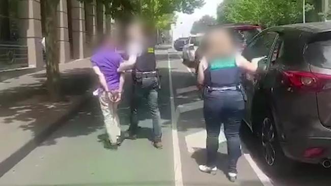 Australian Federal Police escort a man into police headquarters in Melbourne.