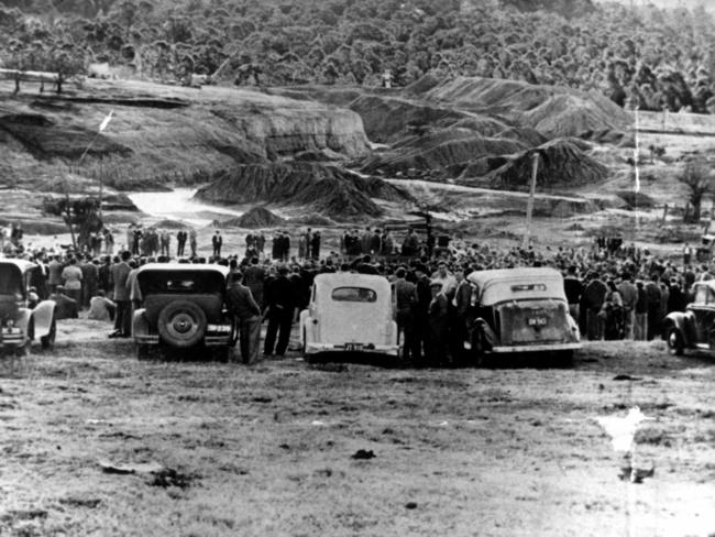 Coal miners watch in silence as army men, with bulldozers and excavators, move in at the open-cut mine at Minmi in 1949.