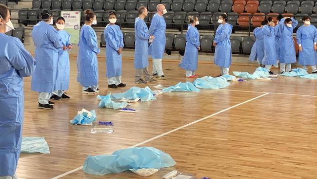 Health workers dressed in PPE ready to test Territorians at the Marrara netball stadium this morning. Picture: Gary Shipway