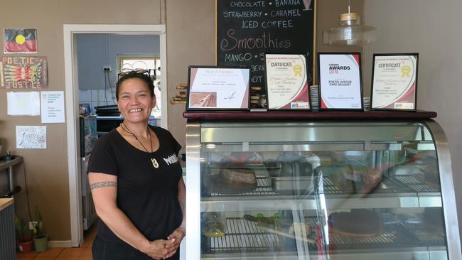 Gayle Joyce stands beside the many awards her Poetic Justice Cafe Gallery has won.