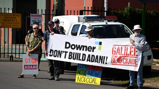 Protesters opposing the Adani coal mine in the Galilee Basin hold signs outside the Downer Rail workshop during a visit by Queensland Premier Annastacia Palaszczuk in Maryborough, Monday, September 11, 2017. The Palaszczuk Government has today confirmed a $70 million pipeline of projects for Downer EDI's Maryborough workshop. (AAP Image/Dan Peled) NO ARCHIVING