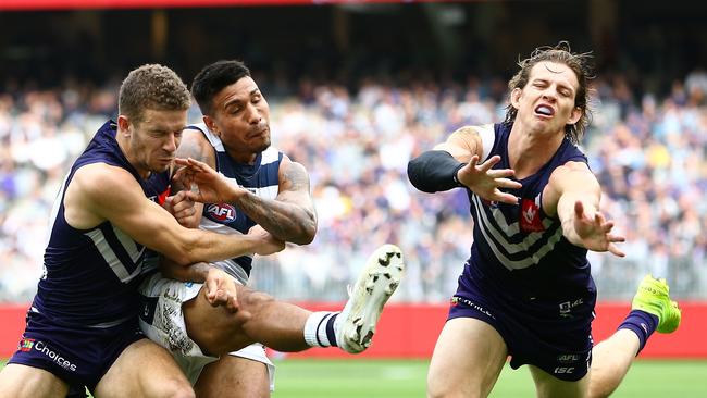 Tim Kelly of the Cats kicks forward under pressure from Sam Switkowski and Nat Fyfe of the Dockers during the Round 20 AFL match between the Fremantle Dockers and the Geelong Cats at Optus Stadium in Perth, Saturday, August 3, 2019.  (AAP Image/Gary Day) NO ARCHIVING, EDITORIAL USE ONLY