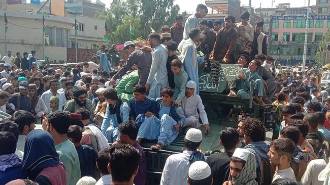 Taliban fighters and local people sit on an Afghan National Army vehicle on a street in Jalalabad province. Picture: AFP