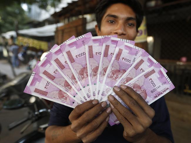 FILE - In this Nov. 11, 2016 file photo, an Indian man displays new currency notes of 2000 Indian rupee in Ahmadabad, India. The sudden withdrawal of 86 percent of India's currency has left cash in short supply, retail sales stumbling and wholesale markets in turmoil. (AP Photo/Ajit Solanki, File)