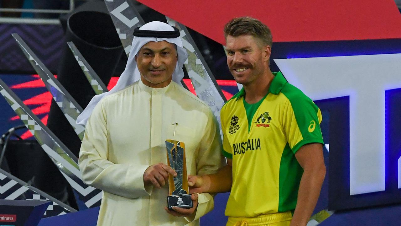 Australia's David Warner (R) receives the Player of the Tournament trophy at the end of the ICC menâ&#128;&#153;s Twenty20 World Cup final match between Australia and New Zealand at the Dubai International Cricket Stadium in Dubai on November 14, 2021. (Photo by INDRANIL MUKHERJEE / AFP)