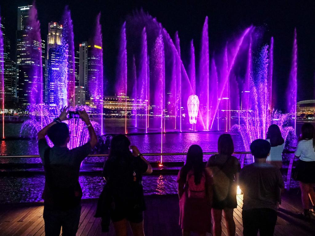 Fans of Swift take pictures of a light and water show in the "Eras Tour Trail" at Marina Bay Sands in Singapore. Picture: Roslan Rahman/AFP