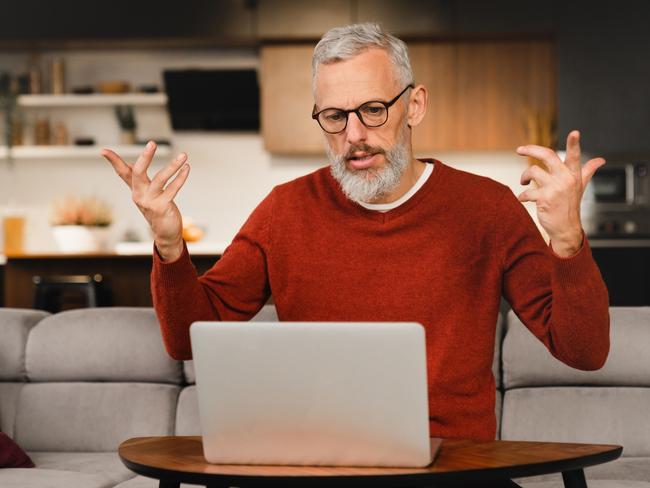 Angry mature middle-aged man businessman freelancer talking with clients colleagues business partners online on laptop, solving problems, explaining at home remotely; investing investor superannuation money generic