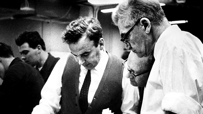 Rupert Murdoch (left), with chief make-up expert Solly Chandler (right) and editorial manager Hank Bateson, looks at a page one proof of The Australian in Canberra on July 15, 1964.