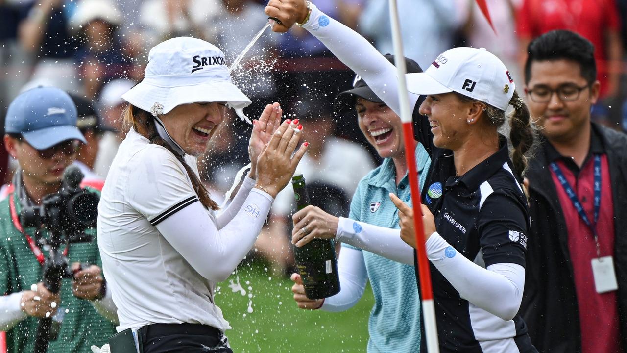 Hannah Green (L) of Australia celebrates with sparkling wine after winning the final round of the HSBC Women's World Championship golf tournament at Sentosa Golf Club in Singapore on March 3, 2024. (Photo by Roslan RAHMAN / AFP)