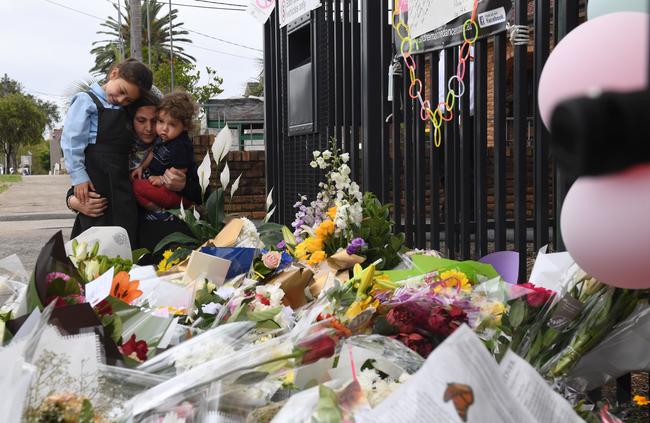 A mother and her young children place flowers outside the Banksia Road Public School. The students returned to school today after yesterday’s tragedy. Picture: Dean Lewins