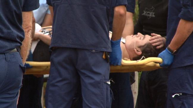 Paramedics and friends comfort the surfer before he was transported to hospital. Picture: TNV