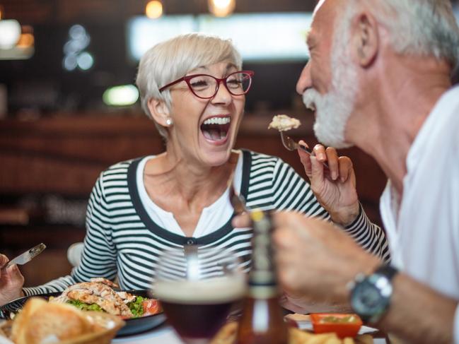 Active senior couple having a lunch in the restaurant and woman is feeding her partner. Drinks and food are on the table. Picture: istock