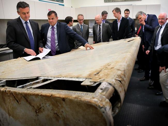 Minister for Infrastructure and Transport Darren Chester and ATSB Chief Commissioner Greg Hood and visiting aviation and air safety experts examine the right outboard main wing flap from MH370 in Canberra today.