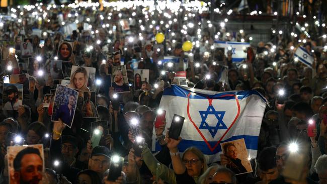 People light their mobile phones and hold portraits of victims during a ceremony commemorating the October 7 attack and the Israeli hostages. Picture: AFP.