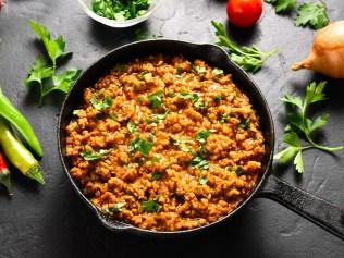 Keema curry in cast iron pan over black stone background. Indian and pakistani style dish. Close up view