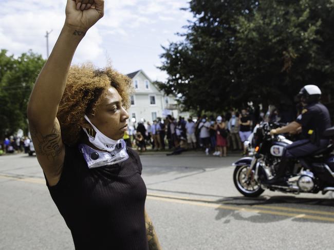 A woman protesting with Black Lives Matter raises her fist as a police motorbike passes the Grace Lutheran Church. Picture: Angus Mordant for NewsCorp Australia