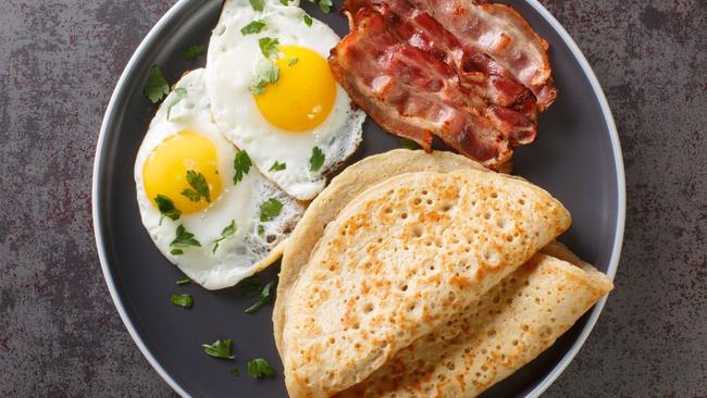 Delicious oatcakes served with egg and bacon close-up in a plate on the table. horizontal top view from above