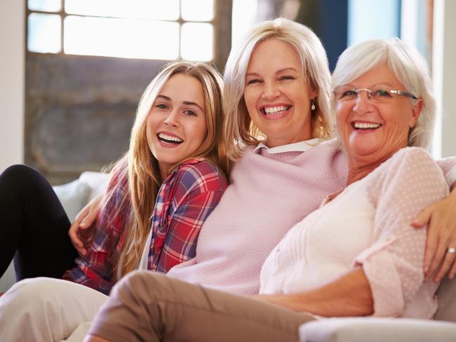 Grandmother With Mother And Adult Daughter Relaxing On Sofa, Smiling To Camera; happy seniors retirement generic family