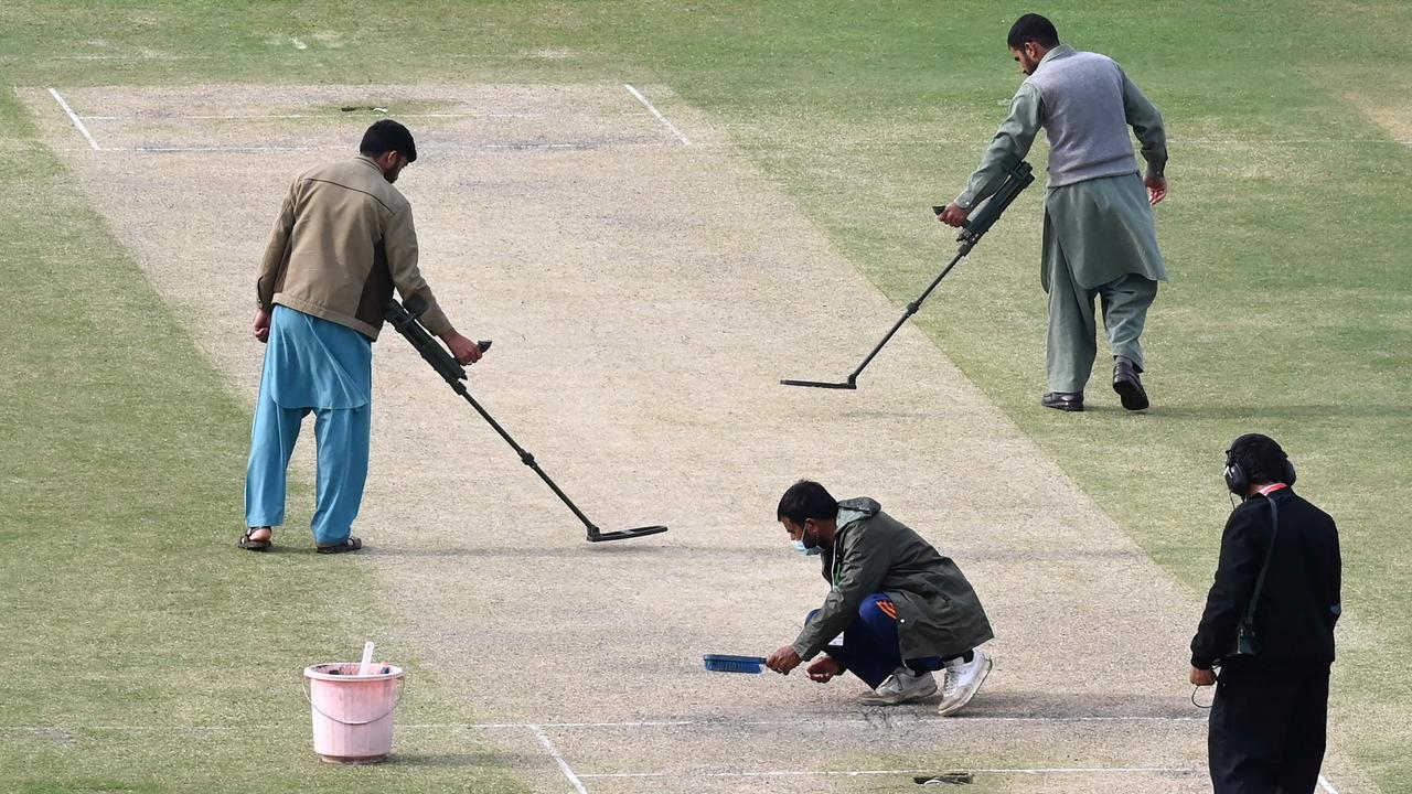 Security personnel use metal detectors on pitch before the start of the fourth day play of the first Test cricket match between Pakistan and Australia at the Rawalpindi Cricket Stadium in Rawalpindi on March 7, 2022. (Photo by Aamir QURESHI / AFP)