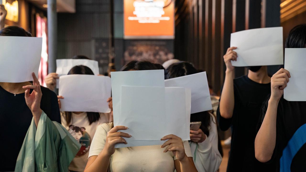 People hold sheets of blank paper in protest of COVID restriction in mainland as police setup cordon during a vigil in the central district on November 28, 2022 in Hong Kong, China. Picture: Anthony Kwan/Getty Images