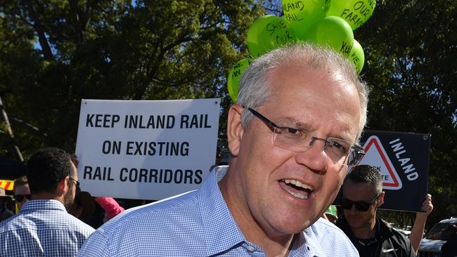 Prime Minister Scott Morrison at the Gilgandra Show in Gilgandra, NSW, on Saturday. In the backgroun are protesters against the inland rail. Picture: AAP Image/Mick Tsikas