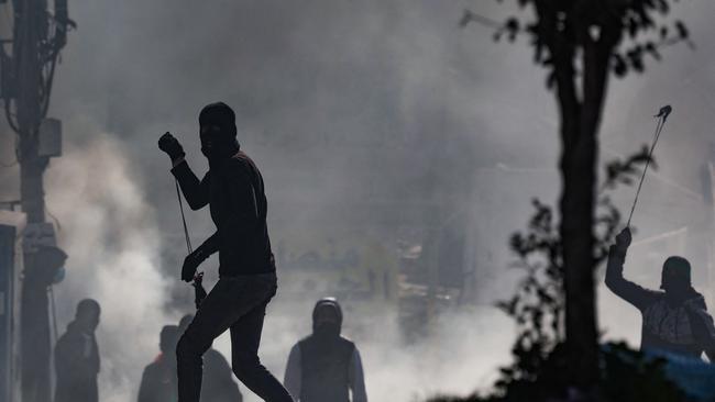 Palestinian demonstrators hurl rocks toward Israeli troops during confrontations with them in the West Bank town of Al-Ram.