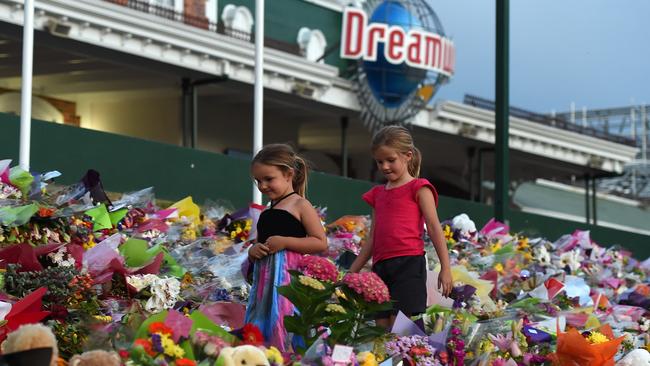 Young girls walk through a floral tribute outside the Dreamworld Theme Park on the Gold Coast in 2016. Picture: AAP Image/Dan Peled.