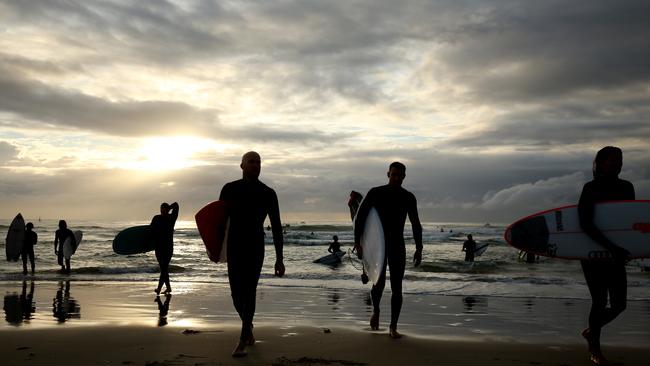 Surfers paddle out as dawn breaks. (Photo by Chris Hyde/Getty Images)