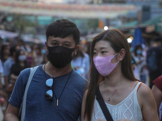 People wearing protective face masks browse stalls. Picture: AFP