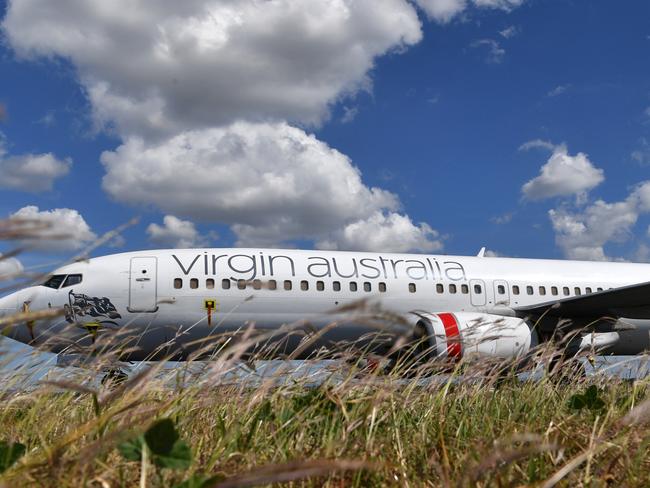 Grounded Virgin Australia aircraft are seen parked at Brisbane Airport in Brisbane, Tuesday, April 7, 2020. Brisbane Airport Corporation (BAC) is working with airlines by accommodating up to 100 grounded aircraft free of charge in response to government-mandated travel restrictions that have grounded a significant proportion of Australia's airline fleet because of the Coronavirus (COVID-19). (AAP Image/Darren England) NO ARCHIVING