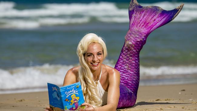 Sandy the Mermaid (Alyce Hill) has a read of the children’s book about her adventures in Surfers Paradise, which began life as a marketing campaign for Sand Safari and is now part of the school curriculum. Photo: Jerad Williams