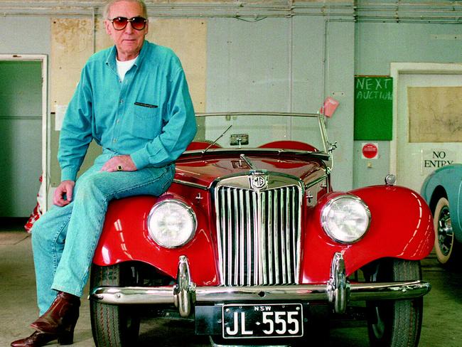 John Laws sits on bonnet of his 1954 MG, one of his collection of restored cars up for auction in 1994. “I loved driving too fast.”