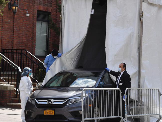 A hearse car backs into a refrigerated truck to pick up deceased bodies outside of the Brooklyn Hospital on April 1, 2020 in New York City. (Photo by Angela Weiss / AFP)