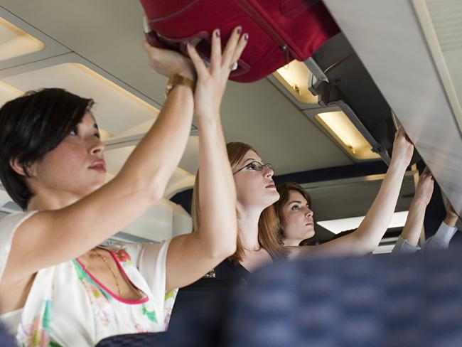 Passengers putting carry on luggage in lockers on a plane. Picture: iStock