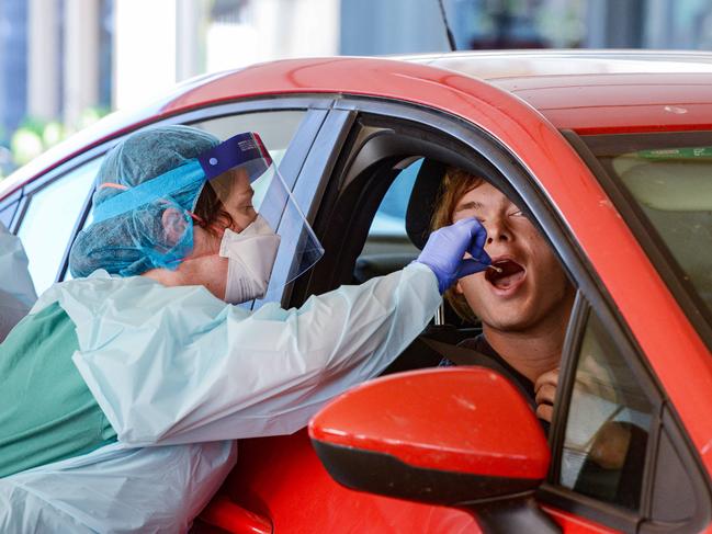 A nurse takes a swab from the first person to use the drive-through coronavirus test station. Picture: AAP / Brenton Edwards