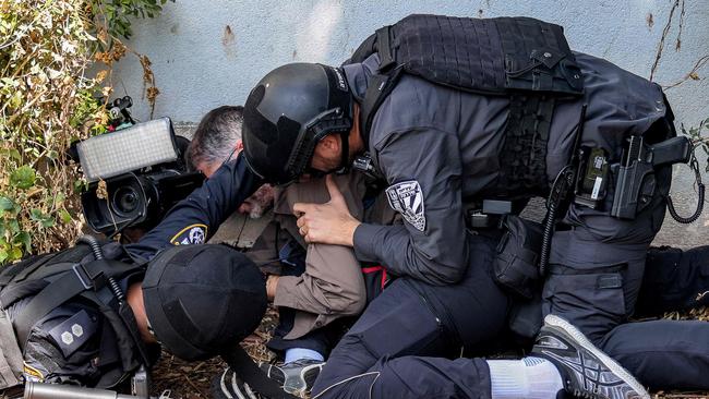 Israeli police and security forces assist a journalist taking cover during an alert for a rocket attack in Israel's southern city of Sderot. Picture: Menahem Kahana / AFP