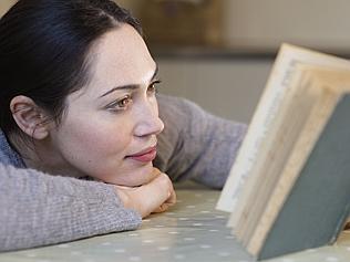 Woman reading book in Kitchen. Getty generic