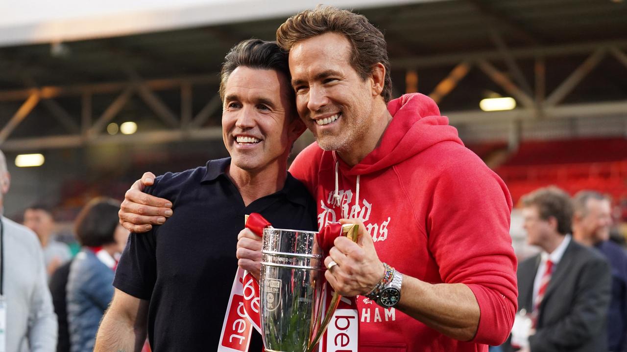 Rob McElhenney and Ryan Reynolds, co-owners of Wrexham AFC, pose for a photo with the trophy following the club's promotion to the Sky Bet Championship during the Sky Bet League One match between Wrexham AFC and Charlton Athletic FC at Racecourse Ground on April 26. Picture: Getty Images