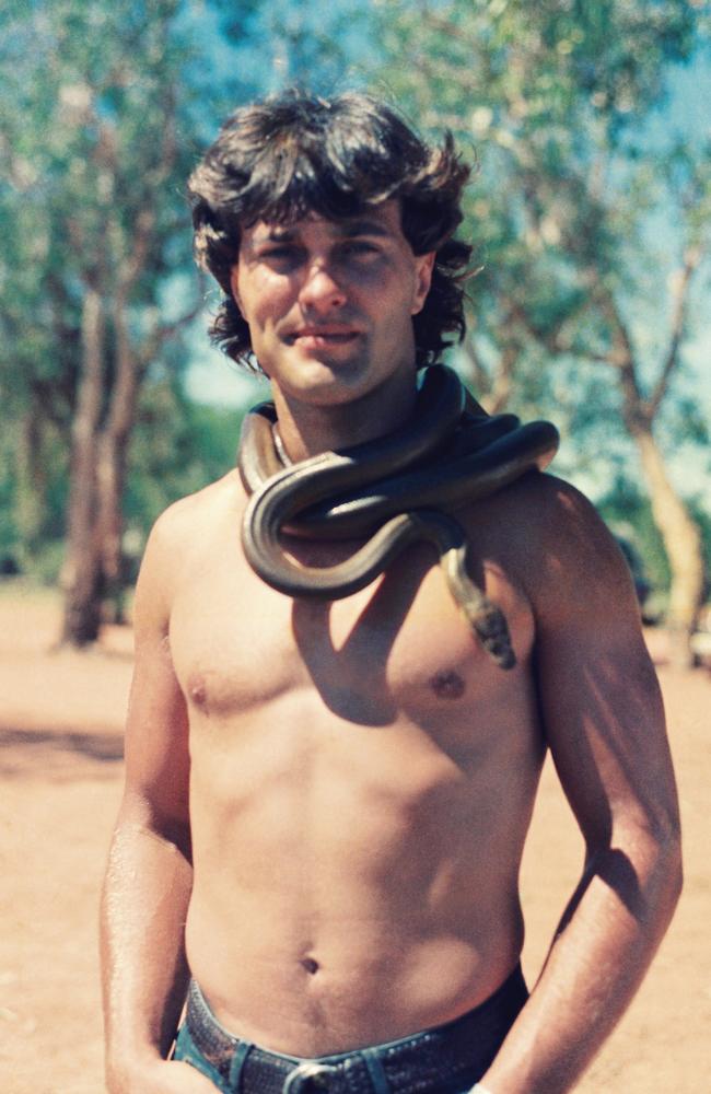 ‘Yellow belly black snake, sleeping on a red rock’ … actually it’s an olive python resting on Oils manager Gary Vasicek in the NT, 1986. From The Silver River by Jim Moginie, published March 2024.