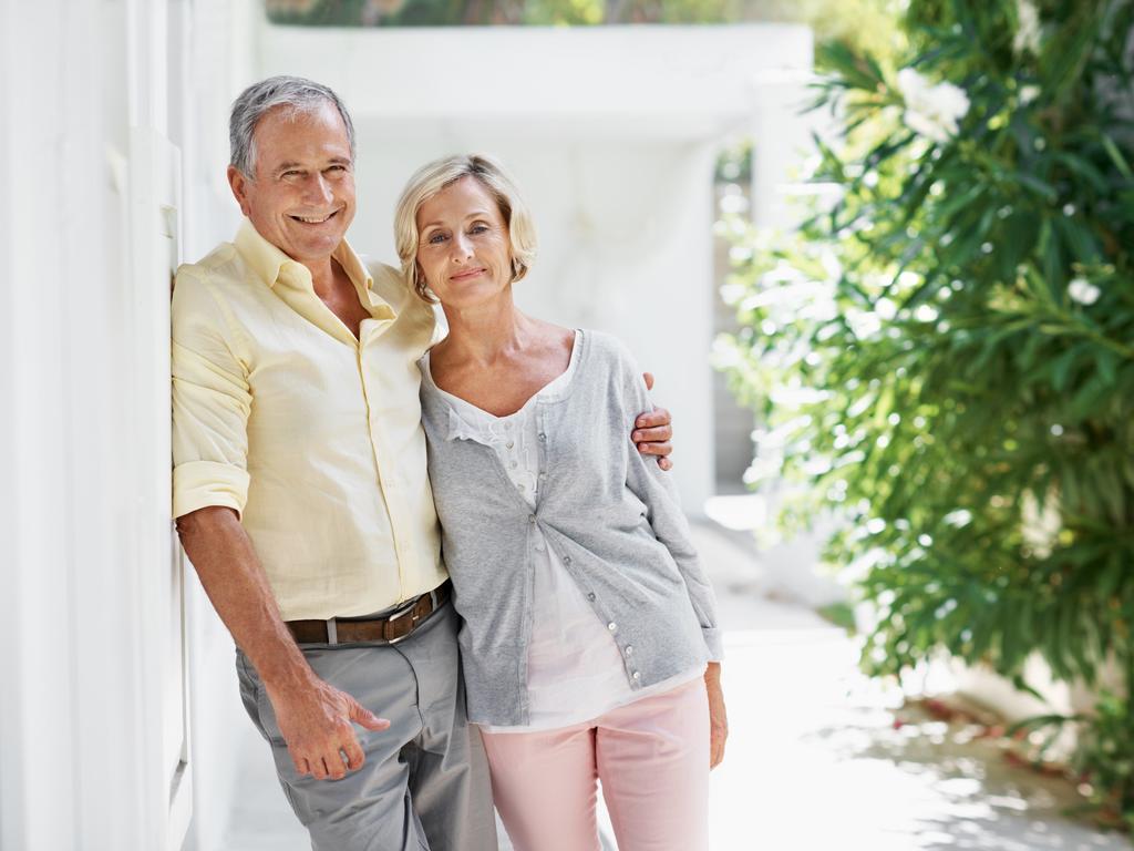 Portrait of an older couple posing for the camera in front of their house with copy space; Senior homeowner couples at home, mortgage, generic