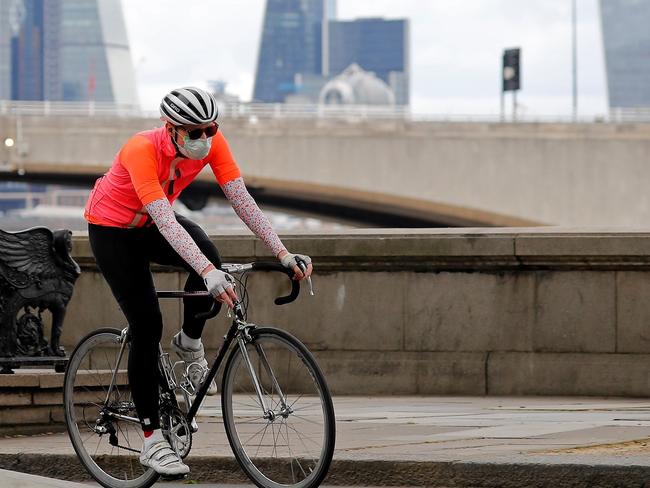 A man wearing PPE (personal protective equipment), including a face mask as a precautionary measure against COVID-19, cycles along Embankment, backdropped by the skyscrapers and office buildings of the City of London, on May 13, 2020, as people start to return to work after COVID-19 lockdown restrictions were eased. - Britain's economy shrank two percent in the first three months of the year, rocked by the fallout from the coronavirus pandemic, official data showed Wednesday, with analysts predicting even worse to come. Prime Minister Boris Johnson began this week to relax some of lockdown measures in order to help the economy, despite the rising death toll, but he has also stressed that great caution is needed. (Photo by Tolga AKMEN / AFP)