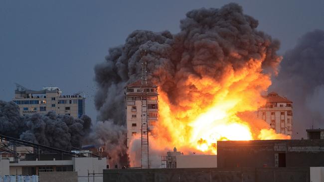 People standing on a rooftop watch as a ball of fire and smoke rises above a building in Gaza City during an Israeli air strike. Picture: AFP