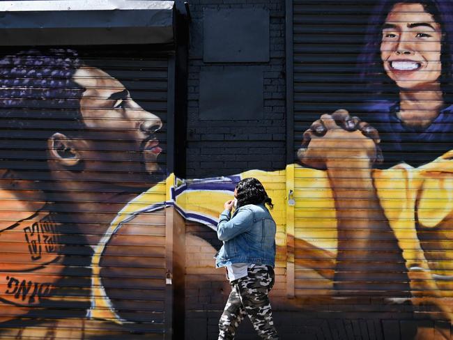 A woman with a face mask walks past a Kobe Bryant and Gianna Bryant in the Brooklyn borough of New York City. Picture: AFP