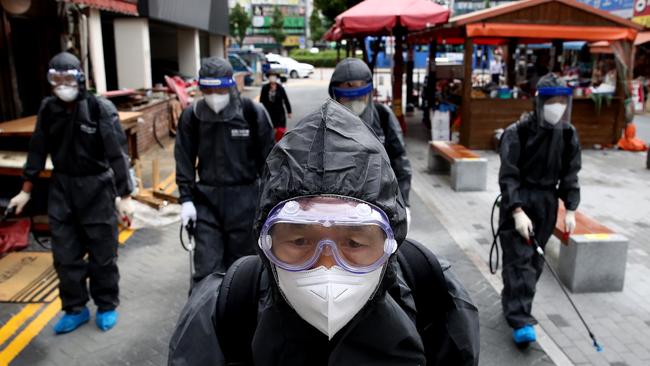 Health officials from Bupyeong district spray antiseptic solution at outside stores in an alley of markets and shopping district in Incheon, South Korea. Picture: Getty