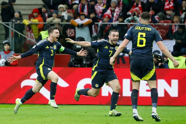 Andrew Robertson (L) celebrates scoringScotland's winner in Warsaw with  John McGinn (C) and  John Souttar (R)