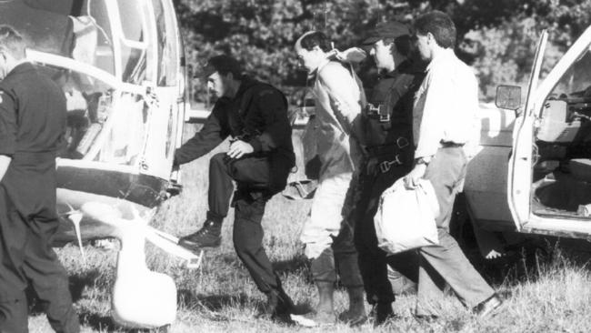 Peter Gibb is led to a helicopter by police. Picture: Craig Borrow