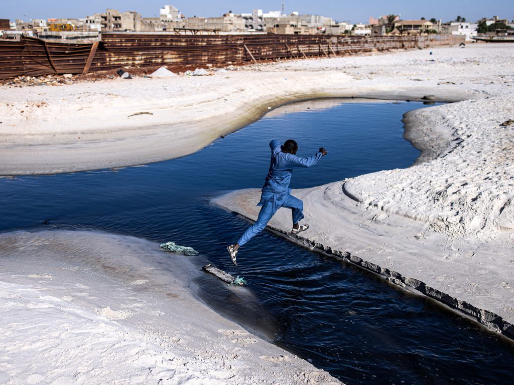 A man jumps over black water pouring out along Hann Bay in Dakar. Once West Africa’s scenic gem, it has been transformed into one of Dakar’s most polluted areas. Picture: John Wessels/AFP